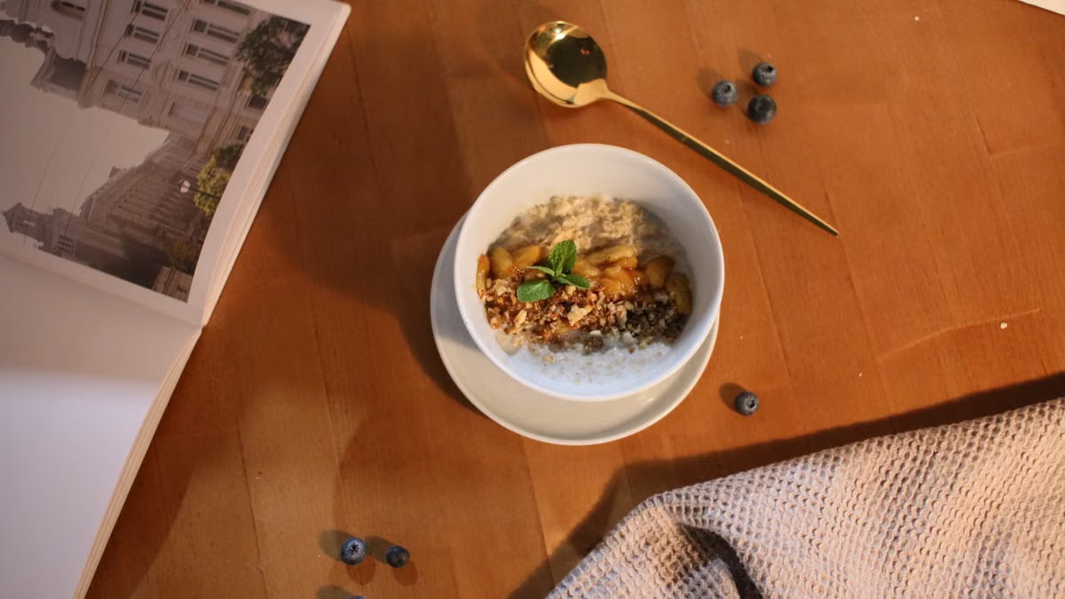 A delicious oatmeal bowl topped with nuts and mint on a wooden table.